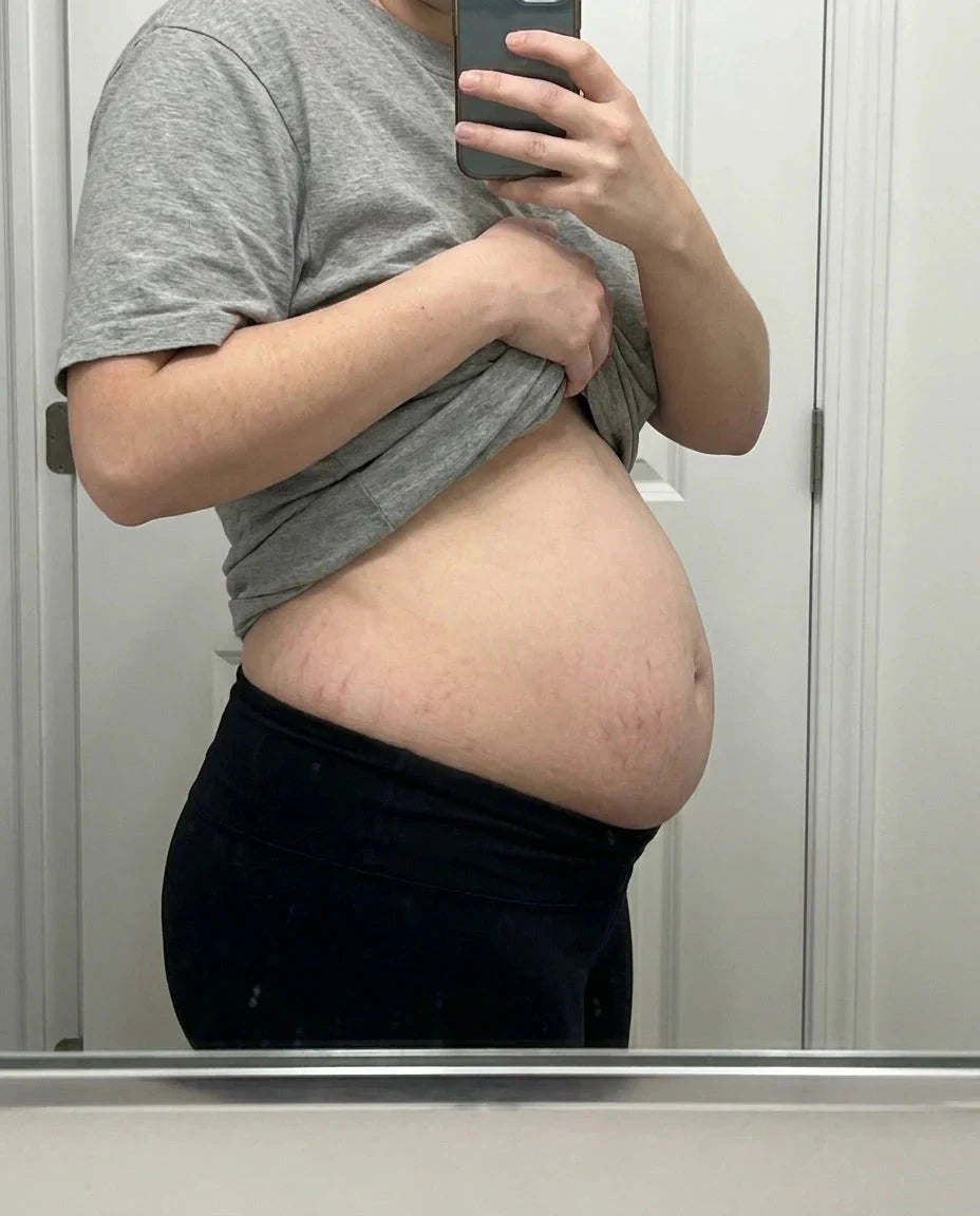 Ventre post-partum de profil devant un miroir